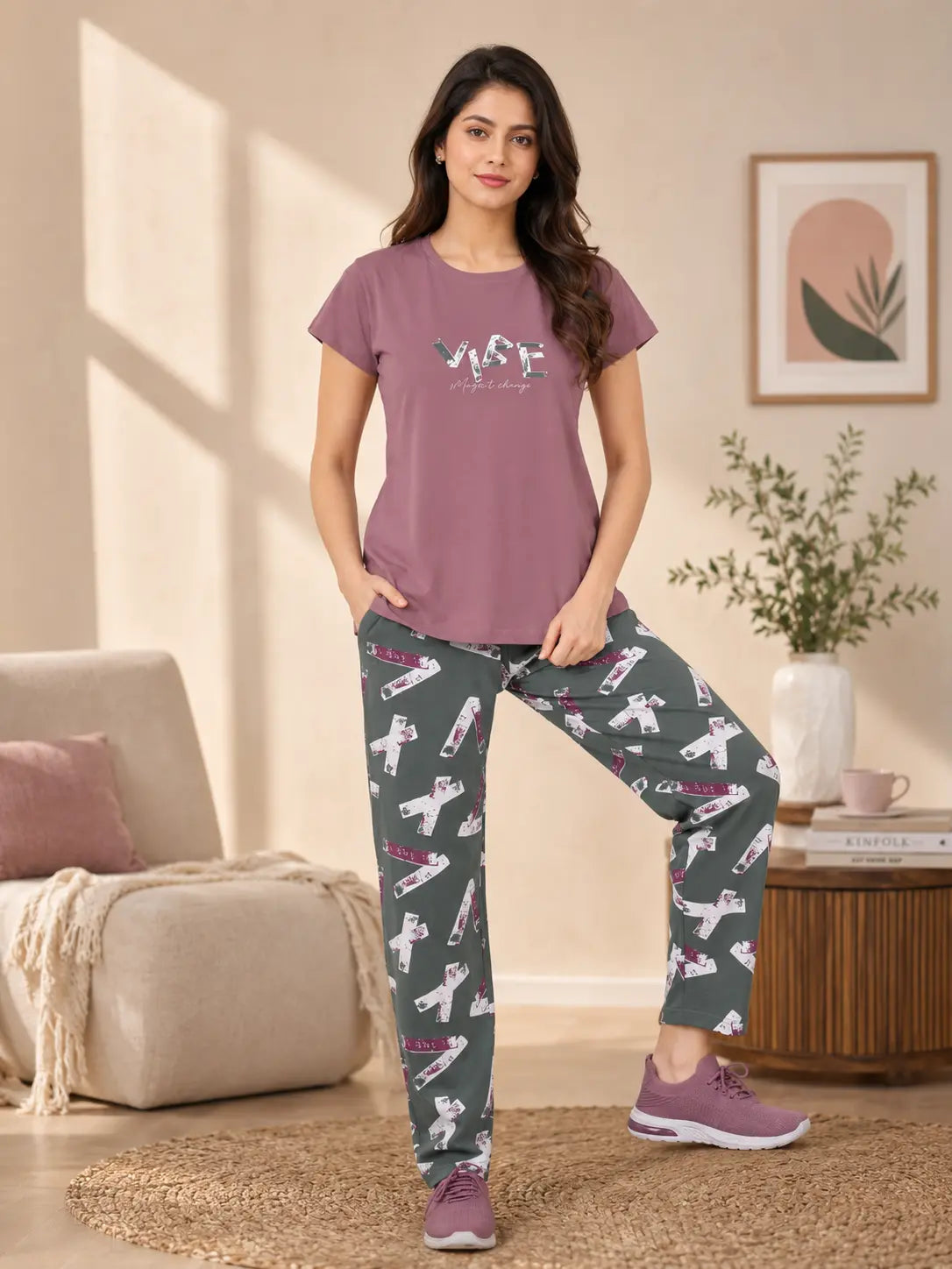 Woman wearing a purple t-shirt and patterned pants in a living room.
