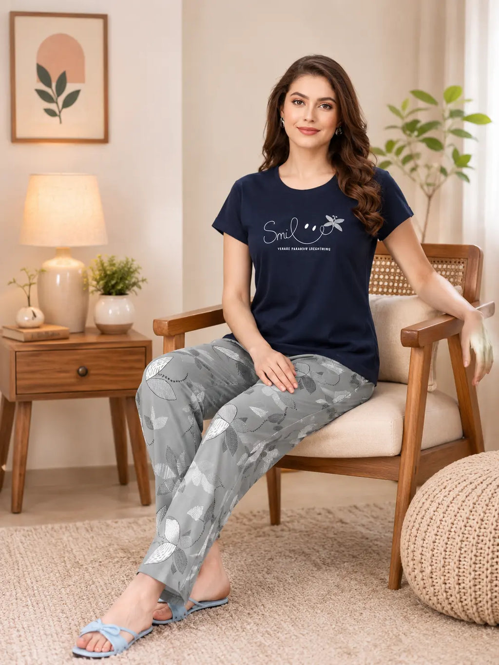 Woman sitting on a chair wearing a navy blue t-shirt and gray patterned pants in a cozy living room.