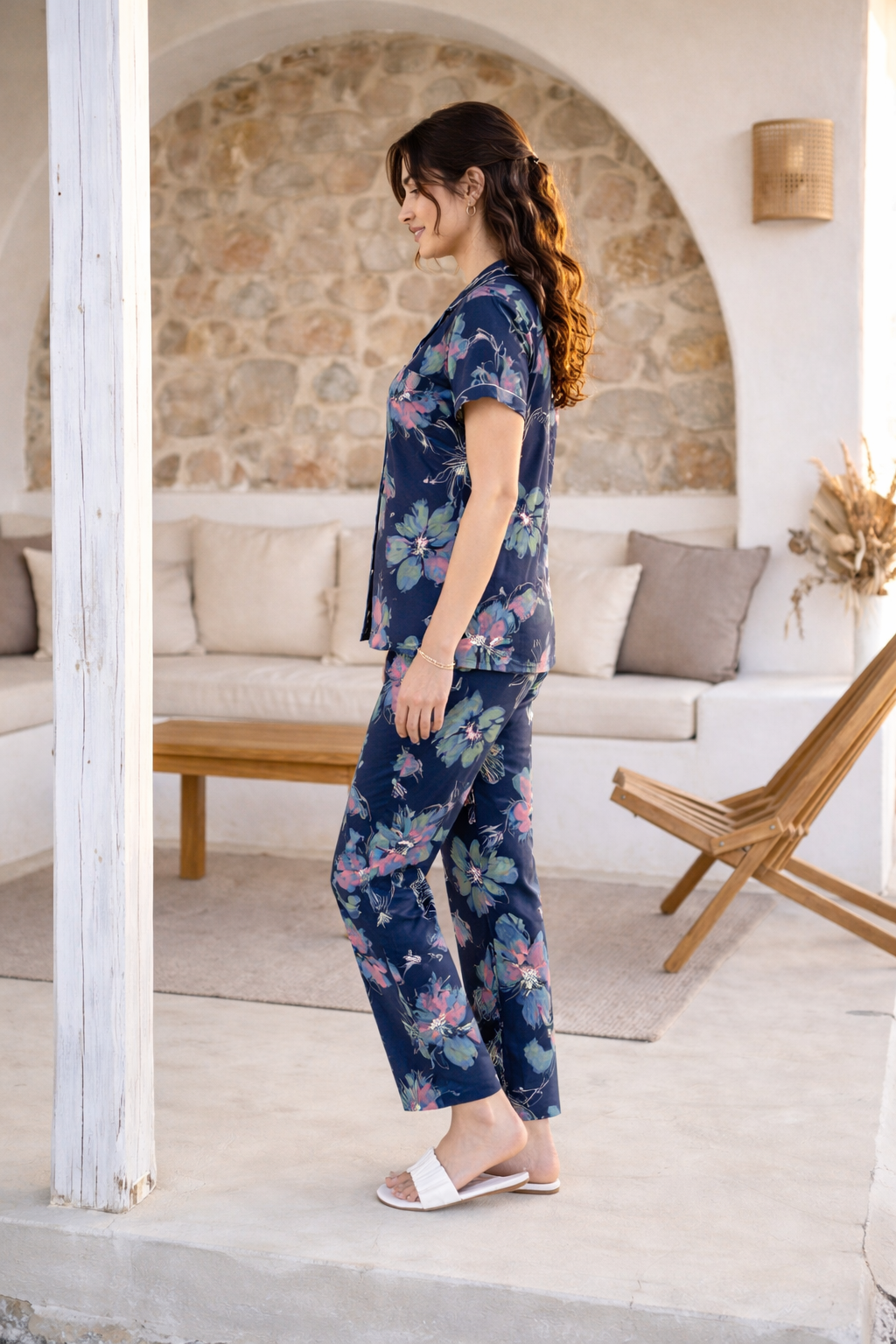 Woman in a navy floral pajama set standing in a cozy living room.