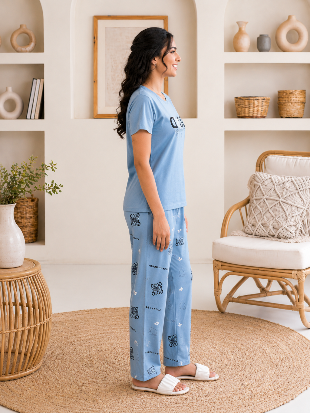 Woman wearing a light blue pajama set in a cozy living room.