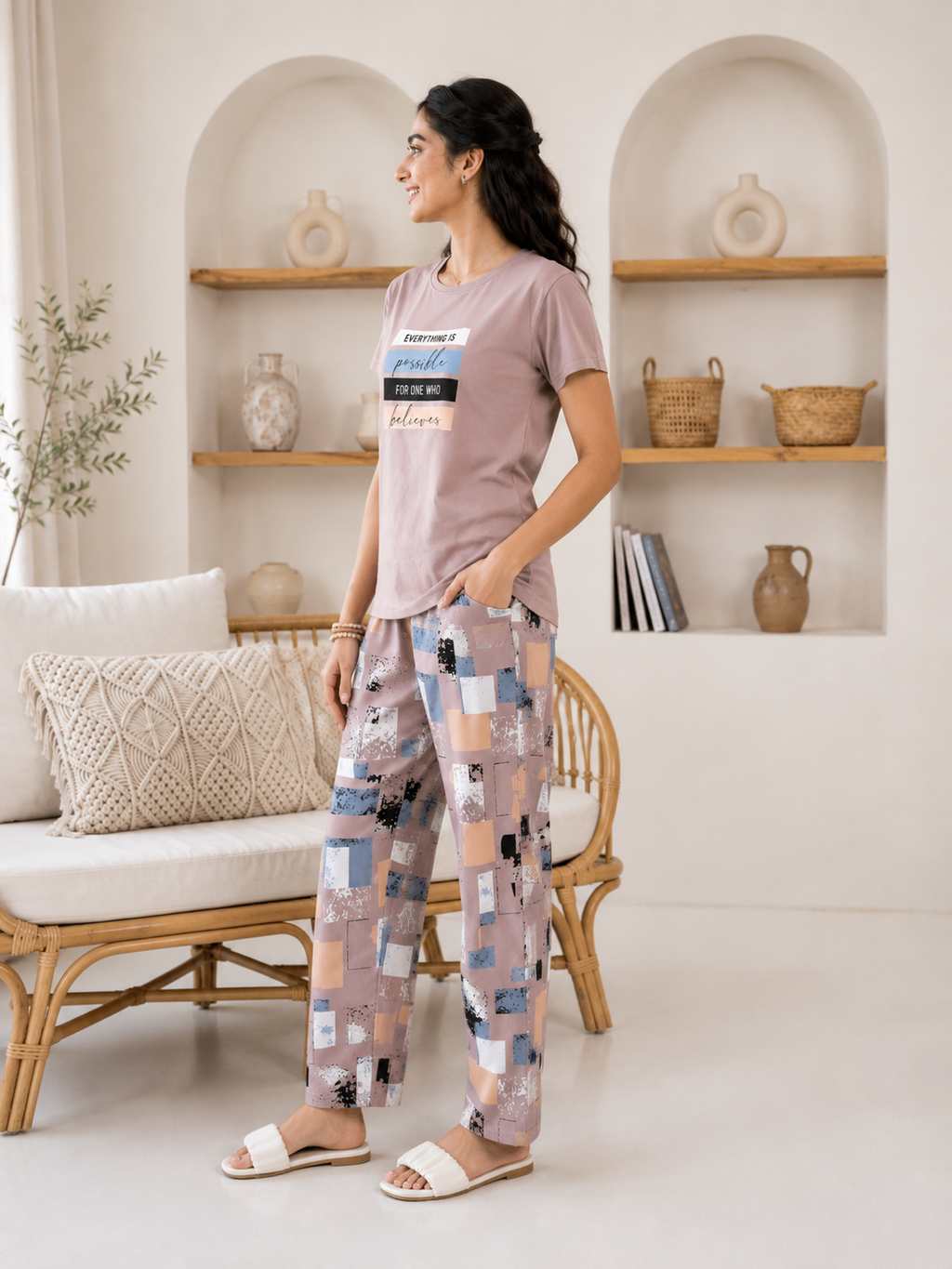 Woman wearing a casual outfit with a t-shirt and patterned pants in a home setting.