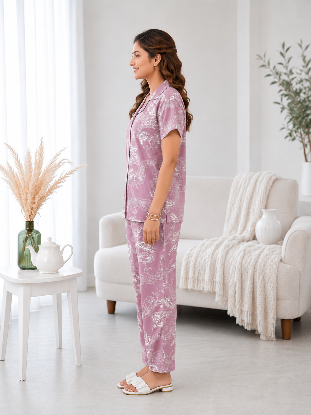 Woman wearing a pink pajama set in a bright living room.