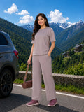 Woman in a gray outfit standing next to a car with mountains in the background