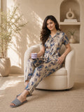 Woman in floral pajama set sitting on a chair in a cozy room.