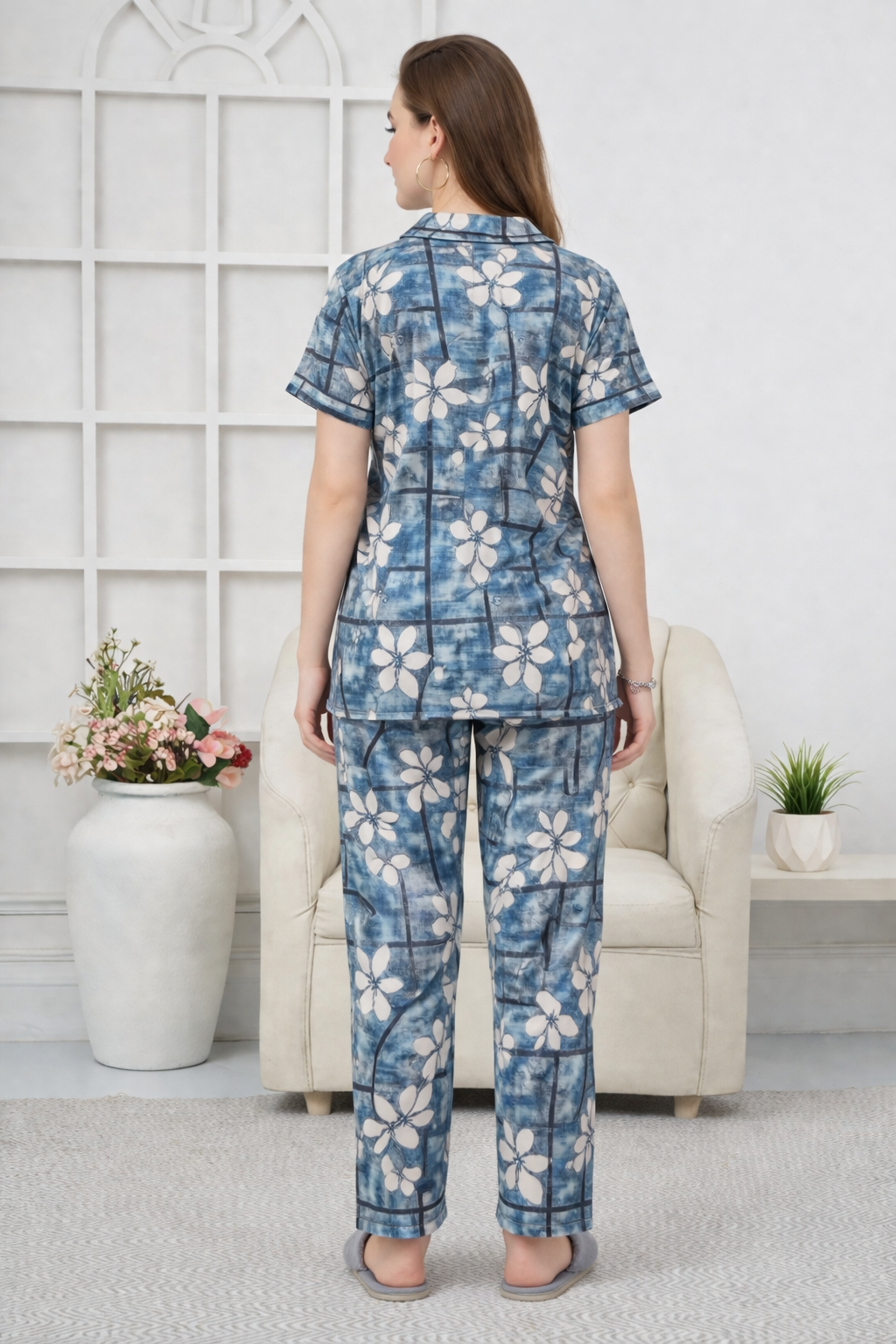 Woman wearing a blue floral pajama set in a room with white walls and decor.