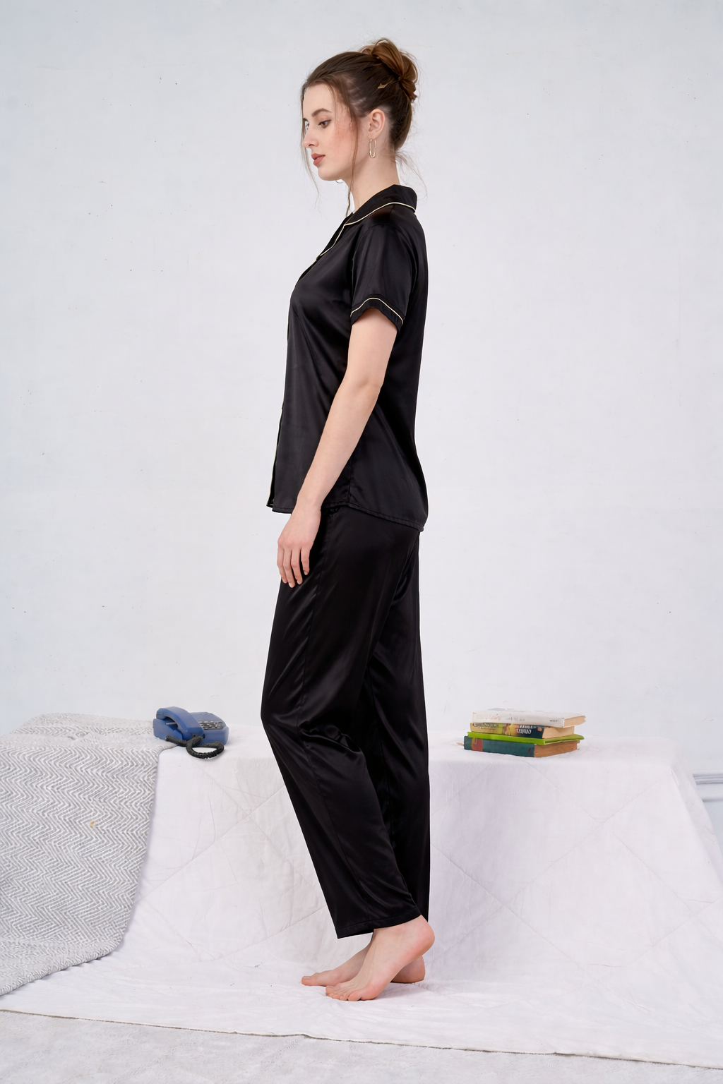 Woman wearing a black outfit standing on a white rug with a light gray couch and books in the background.
