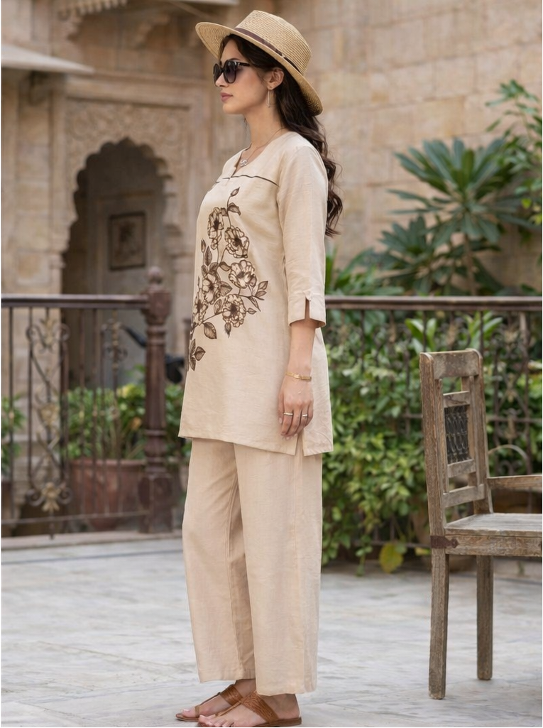 Woman in beige outfit with hat standing in a garden setting