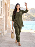 Woman in green outfit standing by a scenic coastal area