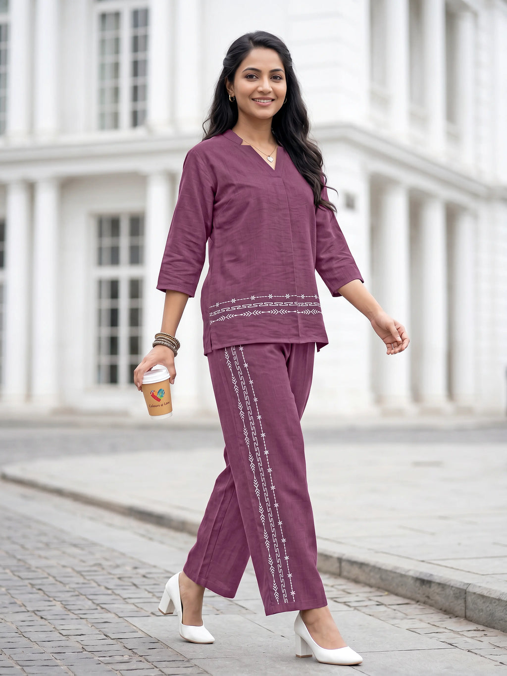 Woman in a purple outfit walking outdoors with a white building in the background
