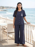 Woman in navy outfit standing on a balcony with ocean view