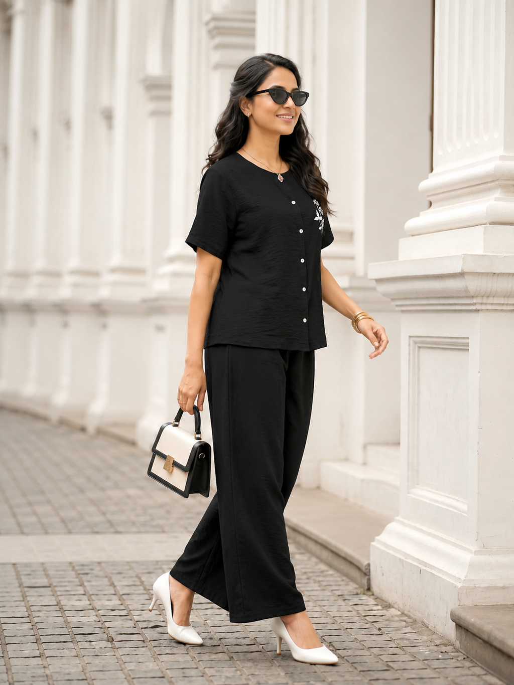 Woman in a black outfit standing in front of a white architectural building.
